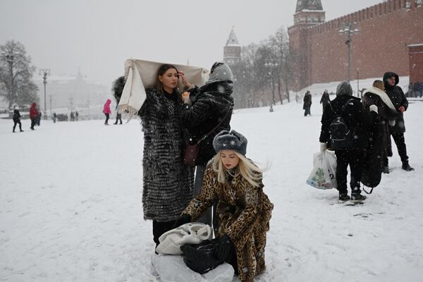 Women prepare to pose for a photo in the snow-covered Red Square in Moscow on December 3, 2023. - Sputnik Africa