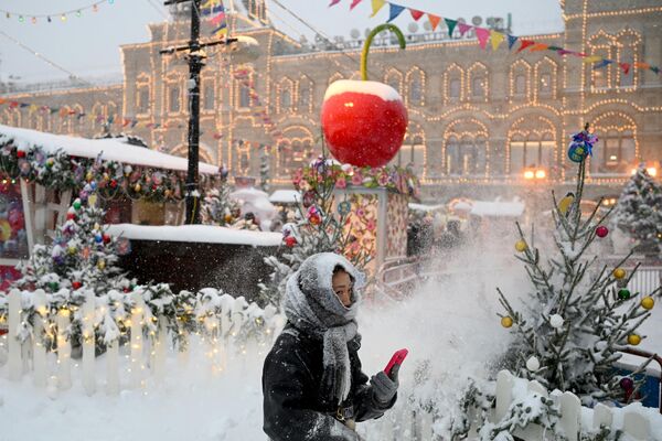 A woman walks past Christmas market stalls in the snow-covered Red Square in Moscow on December 3, 2023. - Sputnik Africa