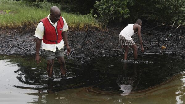 In this Sunday June 20, 2010 file photo, men walk in an oil slick covering a creek near Bodo City in the oil-rich Niger Delta region of Nigeria.  - Sputnik Africa