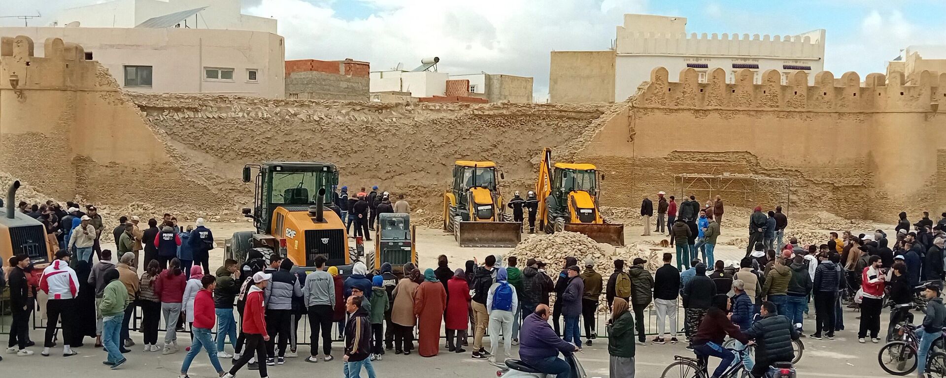 People and Civil Protection members gather at the site of a collapsed section of the ancient wall surrounding historic Kairouan in central Tunisia, killing three workers, on December 16, 2023. - Sputnik Africa, 1920, 17.12.2023