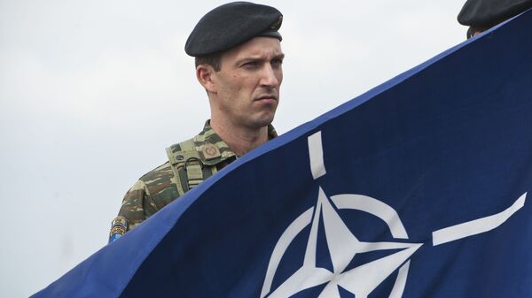 A members of NATO-led peacekeepers in Kosovo (KFOR) holds the NATO flag during the change of command ceremony in Pristina on September 3, 2014.  - Sputnik Africa