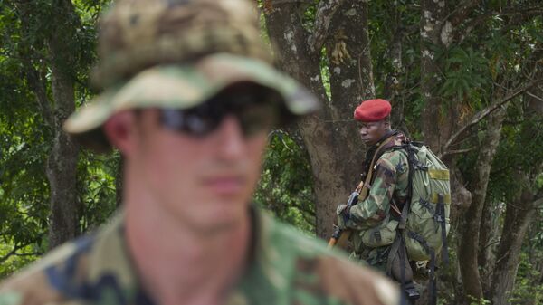 A soldier from the Central African Republic, right, looks across as U.S. Army special forces Captain Gregory, 29, from Texas, left, who would only give his first name in accordance with special forces security guidelines, speaks with other troops from the Central African Republic and Uganda, where they are searching for infamous warlord Joseph Kony, in Obo, Central African Republic, Sunday, April 29, 2012. - Sputnik Africa