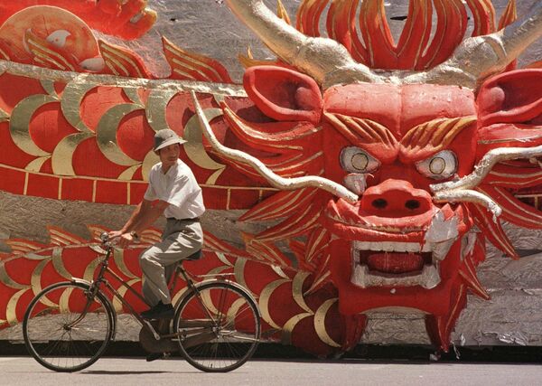 A Chinese man cycles past a float, featuring a dragon head, that was used earlier in the week during performances to celebrate the Hong Kong handover, outside Beijing&#x27;s Workers Stadium Friday July 4, 1997.  - Sputnik Africa