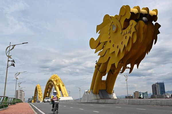 A woman rides a bicycle on Dragon Bridge in Danang on June 24, 2023. - Sputnik Africa