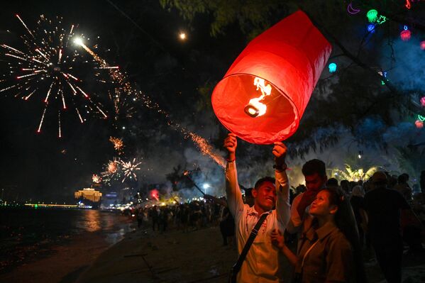 A couple release a lantern as people fire fireworks to mark the arrival of the New Year at a beach in Sihanoukville, the coastal capital of Preah Sihanouk province, on January 1, 2024. - Sputnik Africa