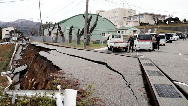 People stand next to large cracks in the sidewalk after being evacuated onto a street in Wajima city, Ishikawa Prefecture. - Sputnik Africa