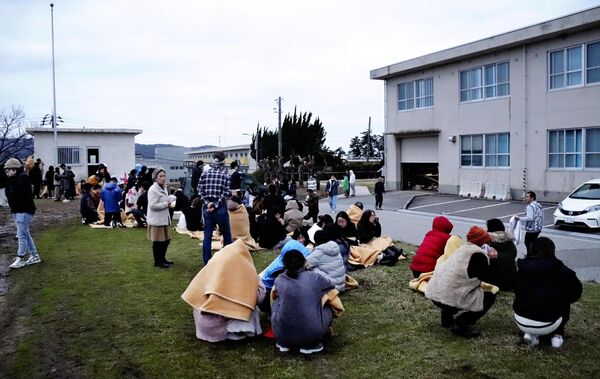 People sit outside in the open after evacuating from buildings in the city of Wajima, Ishikawa prefecture on January 1, 2024, after a major 7.5 magnitude earthquake struck the Noto region in Ishikawa prefecture in the afternoon. - Sputnik Africa