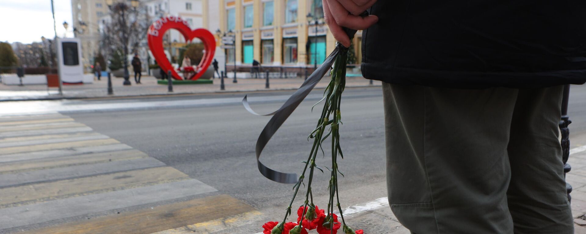 Belgorod resident stands near makeshift memorial to civilians killed in Saturday's Ukrainian missile and MLRS attack on the southwestern Russian city of 340,000. December 31, 2023. - Sputnik Africa, 1920, 01.01.2024