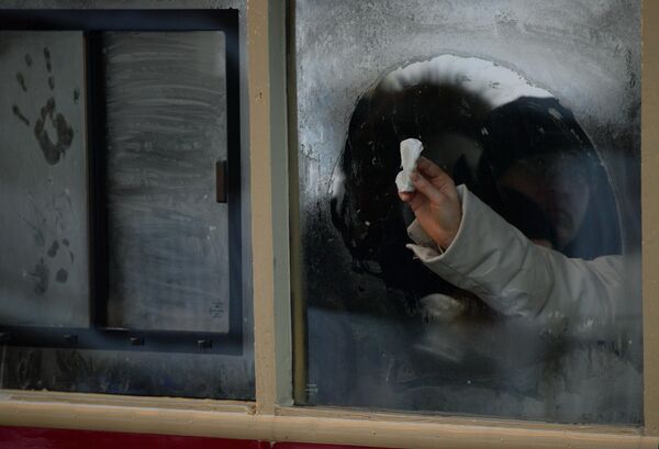 A girl wipes a window in public transport in freezing weather in St. Petersburg. - Sputnik Africa