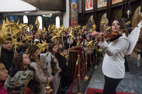 Children holding sticks decorated with stars sing religious songs during a religious service to celebrate Orthodox Christmas in St. Clement Cathedral in Skopje, North Macedonia. - Sputnik Africa