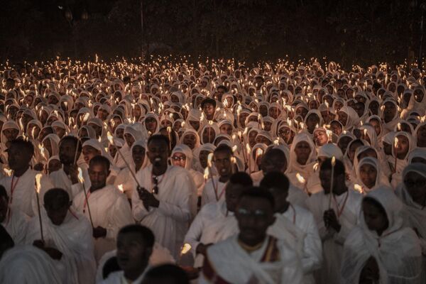 Ethiopian Orthodox worshippers hold candles as they gather to pray ahead of the Ethiopian Orthodox Christmas celebrations at the Bole Medhanialem Church in Addis Ababa, Ethiopia. - Sputnik Africa
