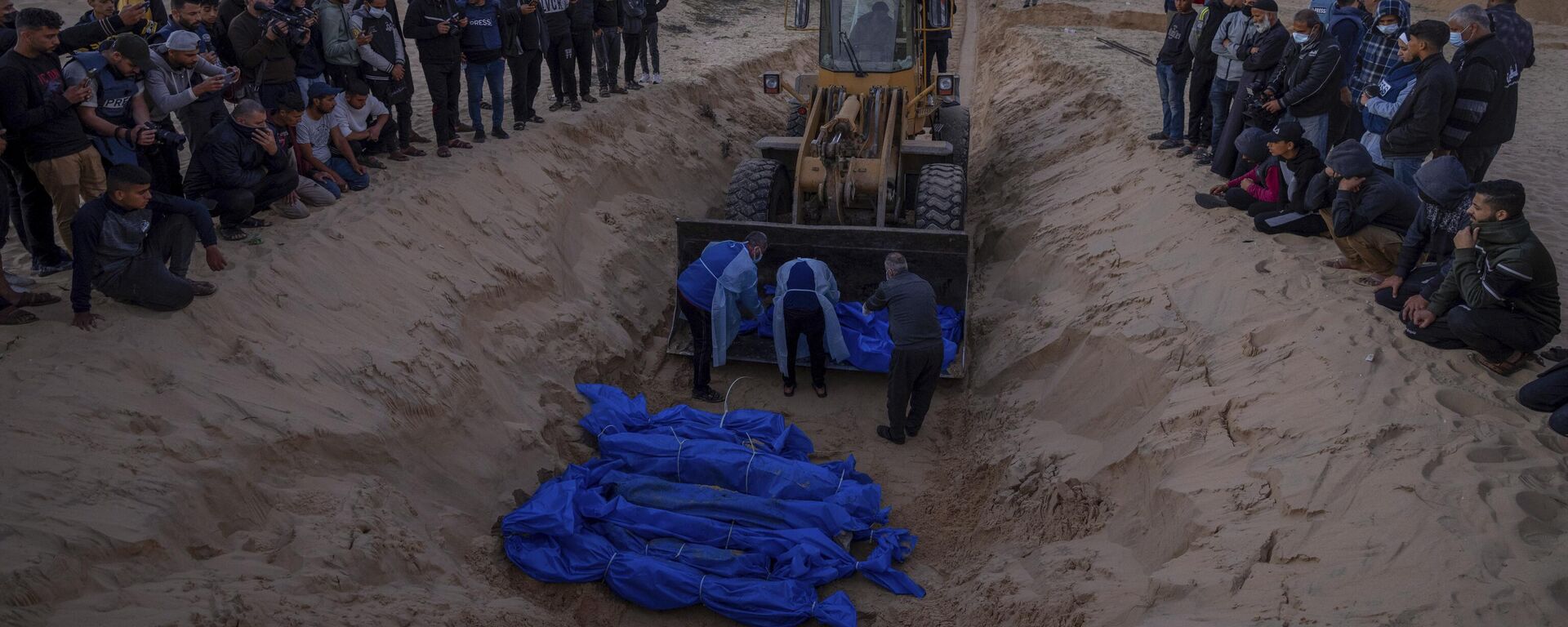 A bulldozer unloads the bodies of Palestinians killed in fighting with Israel and turned over by the Israeli military during a mass funeral in Rafah, Gaza Strip, Tuesday, Dec. 26, 2023.  - Sputnik Africa, 1920, 10.01.2024