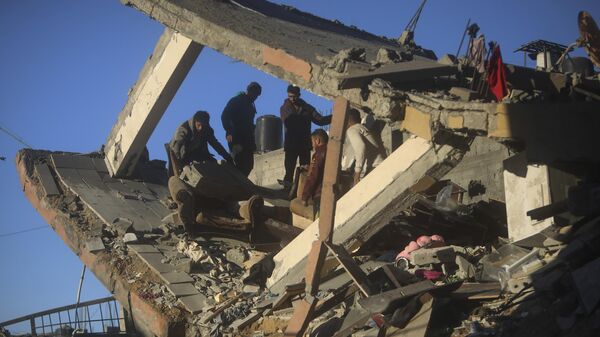 Palestinians inspect the damage of a destroyed house following Israeli airstrikes on Khan Younis, Southern Gaza Strip, Sunday, Jan. 7, 2024. - Sputnik Africa