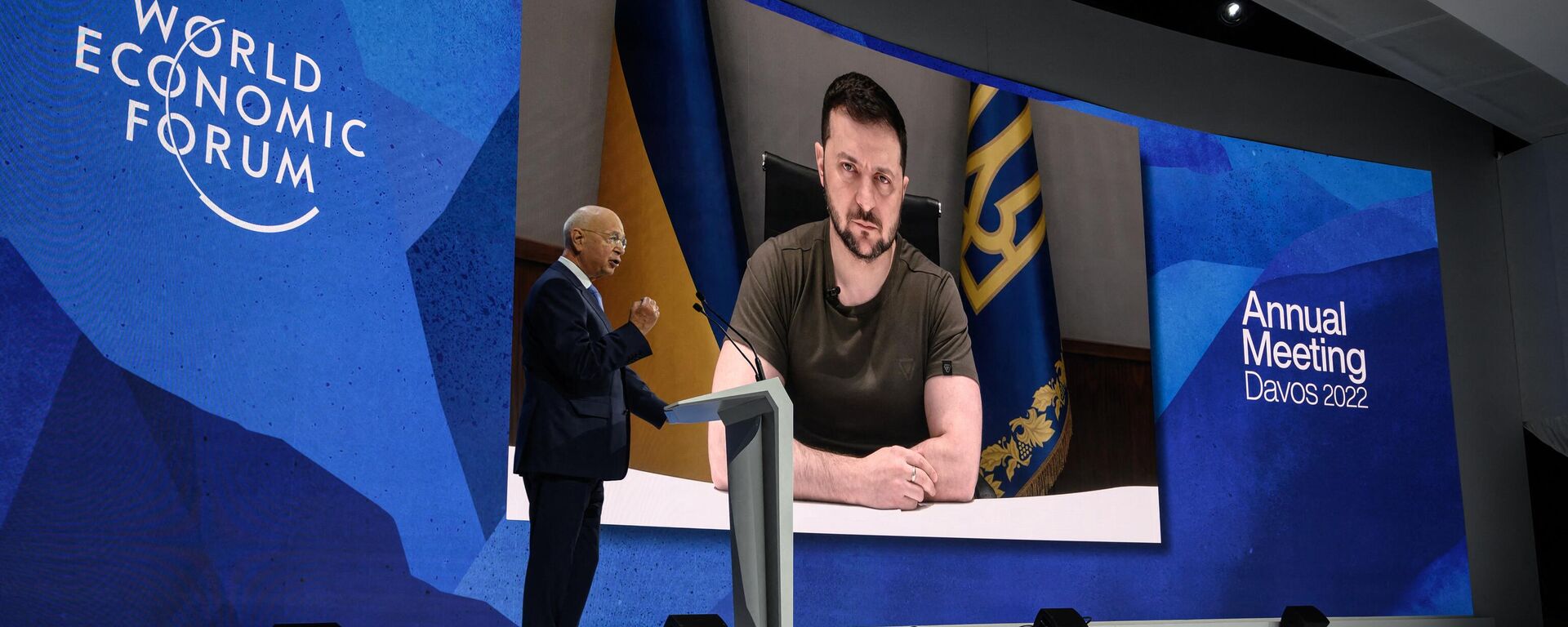  Founder and executive chairman of the World Economic Forum Klaus Schwab welcomes Ukrainian President Volodymyr Zelensky seen on a giant screen by video link at the Congress centre during the World Economic Forum (WEF) annual meeting in Davos on May 23, 2022. Zelensky is similarly expected to attend the WEF's 2024 meetings this week. - Sputnik Africa, 1920, 15.01.2024
