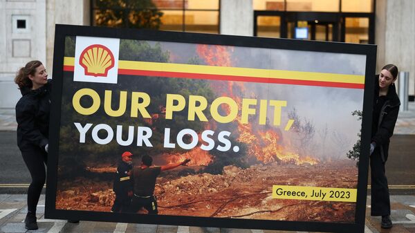 Greenpeace activists hold a spoof advertising billboard featuring the image of a Greek firefighter battling a wildfire near Athens last week with the slogan Our profits, your loss during a protest outside Shell's headquarters in London on July 27, 2023 ahead of the announcement of the energy company's half-year results. - Sputnik Africa