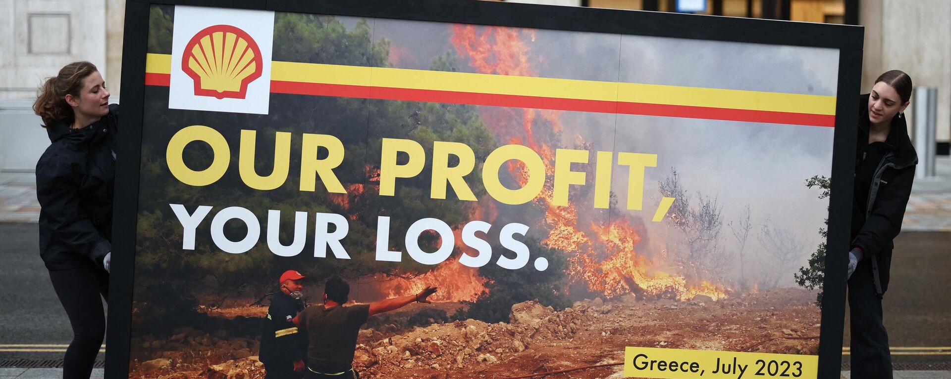 Greenpeace activists hold a spoof advertising billboard featuring the image of a Greek firefighter battling a wildfire near Athens last week with the slogan Our profits, your loss during a protest outside Shell's headquarters in London on July 27, 2023 ahead of the announcement of the energy company's half-year results. - Sputnik Africa, 1920, 17.01.2024