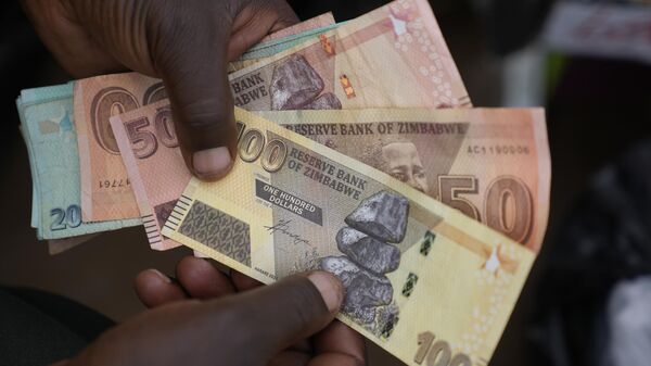 A currency trader holds Zimbabwean dollar notes on the streets of Harare, Zimbabwe, on June, 9, 2022.  - Sputnik Africa
