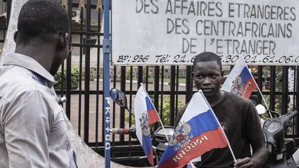 A demonstrator holds a Russian flag with the emblem of Russia on while sitting on a motorcycle in Bangui, on March 22, 2023 during a march in support of Russia and China's presence in the Central African Republic. - Sputnik Africa
