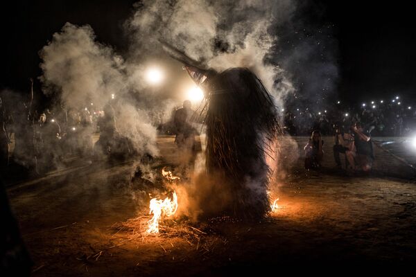 A performer wearing the traditional kumbo mask, a mythological figure of the Jola tribe dressed with palm leaves, whirls in fire during the Kankurang Festival in Janjanbureh on January 27, 2024. - Sputnik Africa