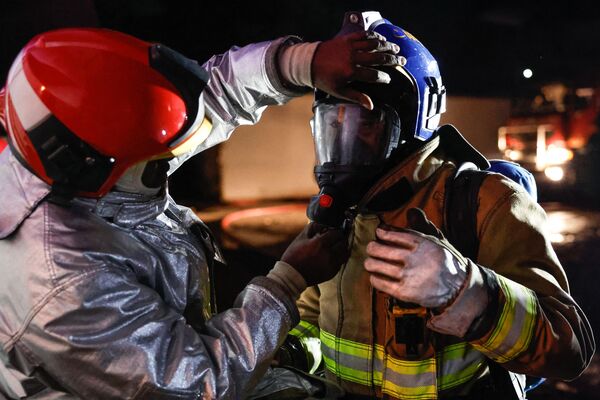 A firefighter adjusts a colleague&#x27;s oxygen mask as they prepare to extinguish a blaze following a series of explosions in the Embakasi area of Nairobi on February 2, 2024.  - Sputnik Africa