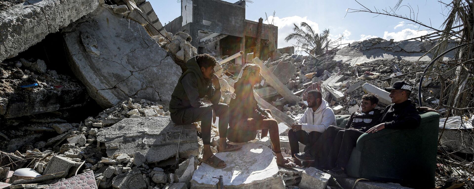 Youths sit together amidst the rubble of a destroyed building in the Maghazi camp for Palestinian refugees, which was severely damaged by Israeli bombardment amid the ongoing conflict in the Gaza Strip between Israel and the Palestinian militant group Hamas, in the central Gaza Strip on February 1, 2024.  - Sputnik Africa, 1920, 02.02.2024