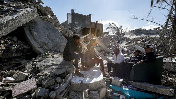 Youths sit together amidst the rubble of a destroyed building in the Maghazi camp for Palestinian refugees, which was severely damaged by Israeli bombardment amid the ongoing conflict in the Gaza Strip between Israel and the Palestinian militant group Hamas, in the central Gaza Strip on February 1, 2024.  - Sputnik Africa