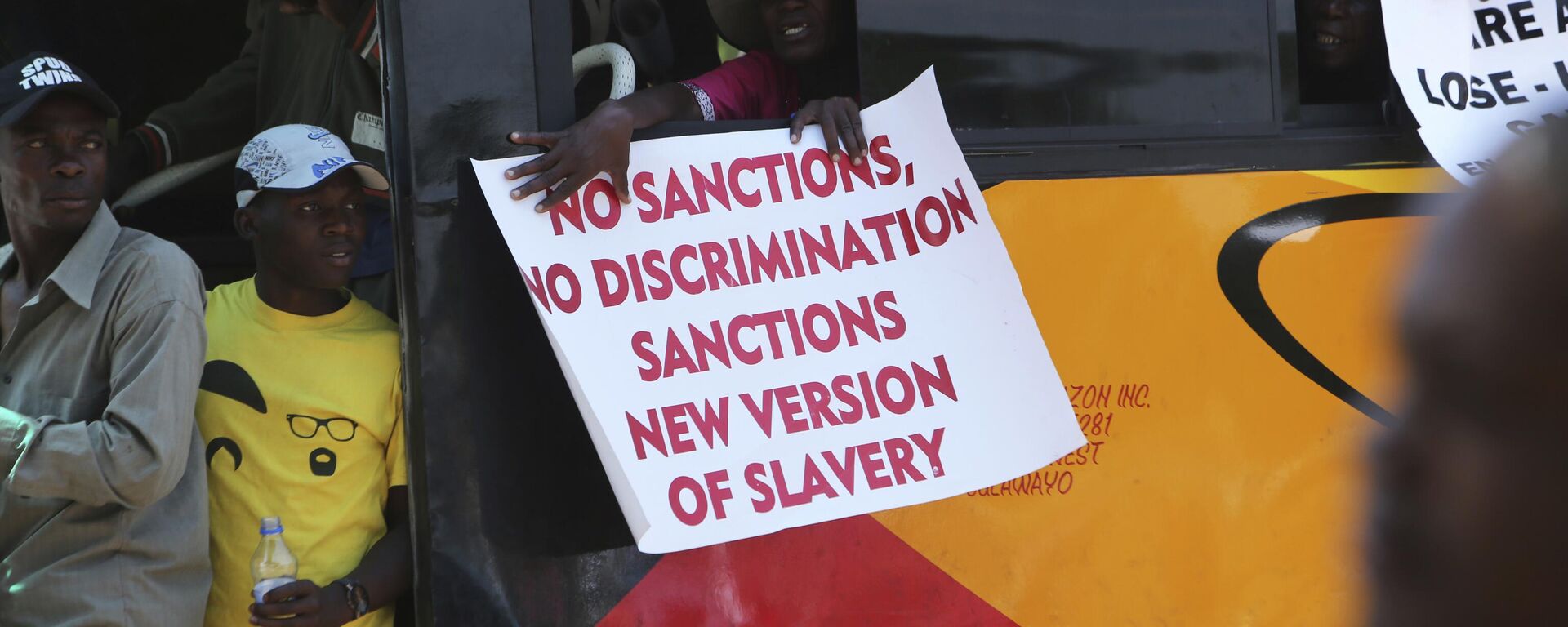 A woman on a bus holds a placard while protesting over US sanctions that the Zimbabwean government blames for the country's worsening economic problems, in Harare, Friday, Oct, 25, 2019. - Sputnik Africa, 1920, 03.02.2024