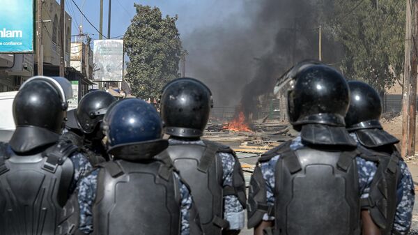 Des policiers sénégalais se tiennent en formation sur une route bloquée par des barricades en feu lors de manifestations convoquées par les partis d'opposition à Dakar le 4 février 2024. - Sputnik Afrique