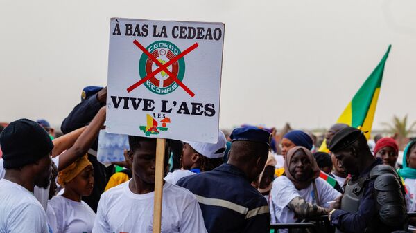 Un partisan de l'Alliance des États du Sahel (AES) tient une pancarte indiquant  À bas la CEDEAO, vive l'ASS  lors d'un rassemblement pour célébrer la sortie du Mali, du Burkina Faso et du Niger de la Communauté économique des États de l'Afrique de l'Ouest (CEDEAO) à Bamako le 1er février 2024 - Sputnik Afrique