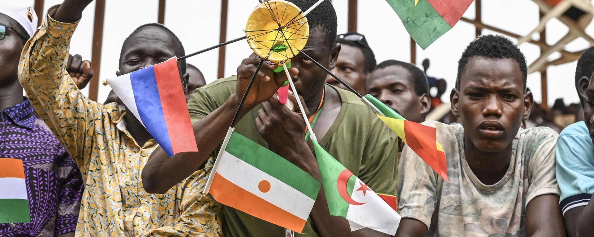 A supporter of Niger's National Council for Safeguard of the Homeland (CNSP) holds national flags of Mali, Burkina Faso, Algeria, Niger and Russia as they gather at the general Seyni Kountche stadium in Niamey on Agust 26, 2023.  - Sputnik Africa, 1920, 12.02.2024