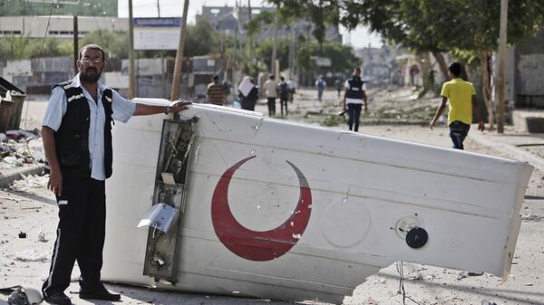 A Palestinian medic shows the cover of a Red Crescent ambulance destroyed by an Israeli strike, as he and residents visit the area during a 12-hour cease-fire in Beit Hanoun, northern Gaza Strip, Saturday, July 26, 2014. - Sputnik Africa