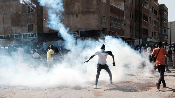 A protester throws back a tear gas canister during clashes with police on the sidelines of a protest against a last-minute delay of presidential elections in Dakar on February 9, 2024. - Sputnik Afrique