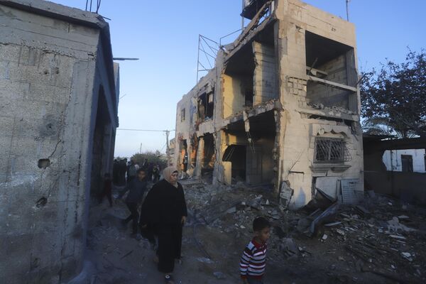 Palestinians walk past a residential building destroyed in an Israeli strike in Rafah, Gaza Strip, Sunday, Feb. 11, 2024. - Sputnik Africa