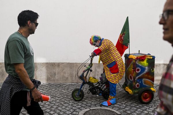 A man dressed up as a clown rides a small motorbike as he takes part in the clown parade in Sesimbra on Feb. 12, 2024. - Sputnik Africa