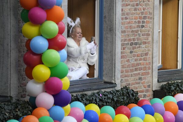 A woman sits at a window, taking a picture of the traditional carnival parade in Duesseldorf, Germany, on Monday, Feb. 12, 2024. - Sputnik Africa