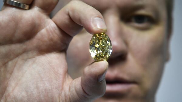 Russian Alrosa Diamond Deputy Director for sales Yevgeny Tsybukov shows a coloured, fancy brownish greenish yellow oval diamond, 50,21 carats, at Alrosa Diamond Cutting Division in Moscow on July 3, 2019.  - Sputnik Africa