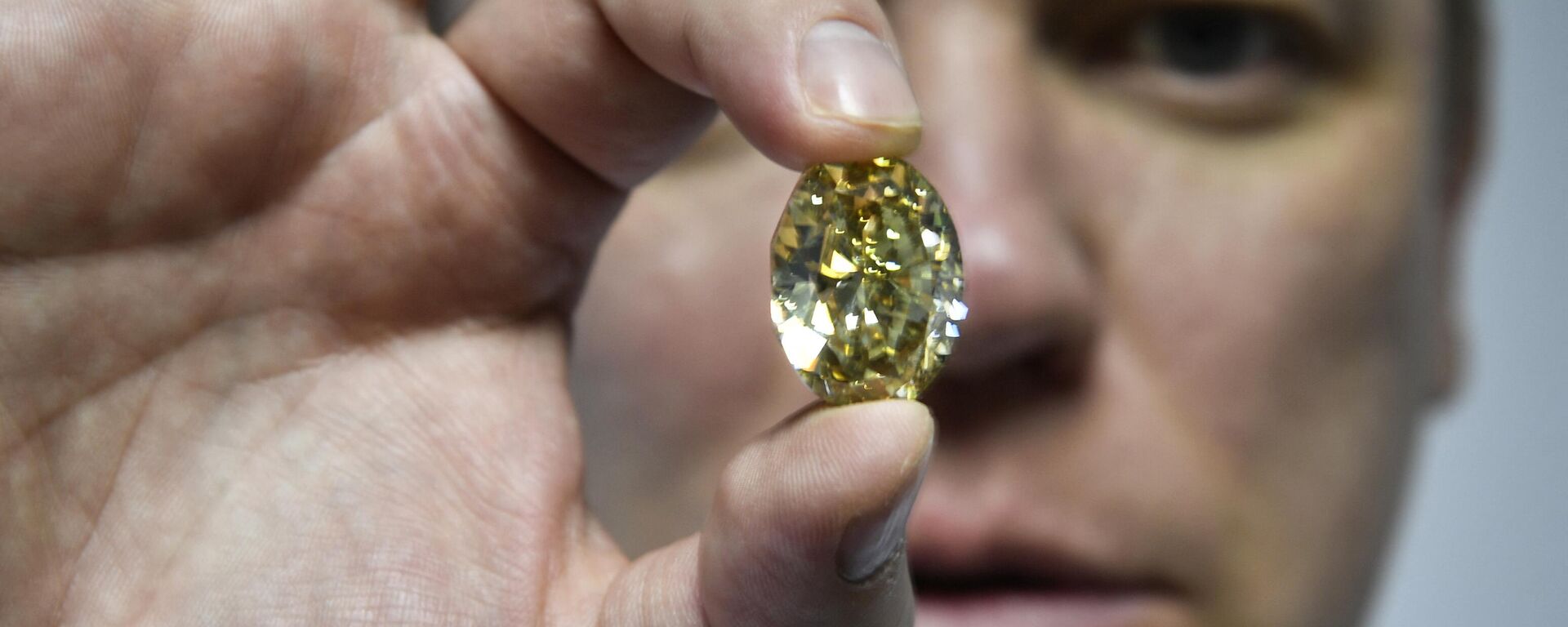 Russian Alrosa Diamond Deputy Director for sales Yevgeny Tsybukov shows a coloured, fancy brownish greenish yellow oval diamond, 50,21 carats, at Alrosa Diamond Cutting Division in Moscow on July 3, 2019.  - Sputnik Africa, 1920, 13.02.2024