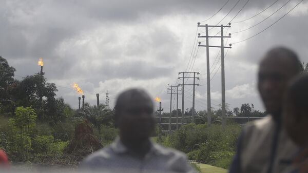 Local people stand and talk with gas flares belonging to the Agip Oil company in the background in Idu, Niger Delta area of Nigeria, Friday, Oct. 8, 2021.  - Sputnik Africa