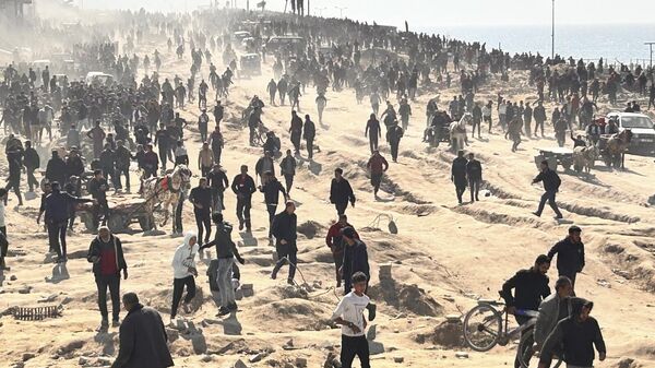 Palestinians wait for humanitarian aid on a beachfront in Gaza City, Gaza Strip, Sunday, Feb. 25, 2024. - Sputnik Africa