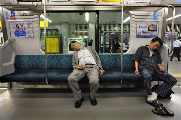 Two passengers sleep as they travel on the Japan Railways (JR) above-ground commuter line of the subway train system of Tokyo on June 17, 2008. - Sputnik Africa