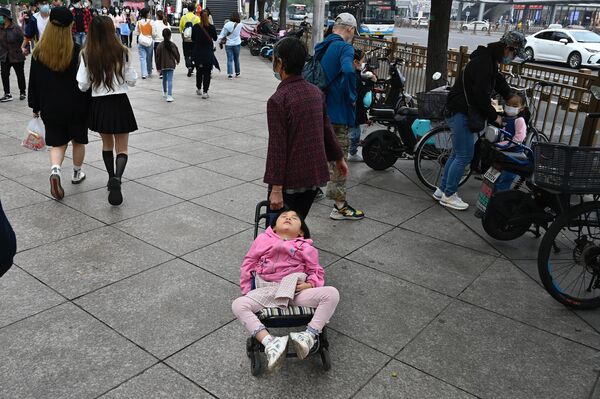 A woman pulls a trolley with a sleeping child along a street during the country&#x27;s national &quot;Golden Week&quot; holiday in Beijing on October 2, 2021. - Sputnik Africa