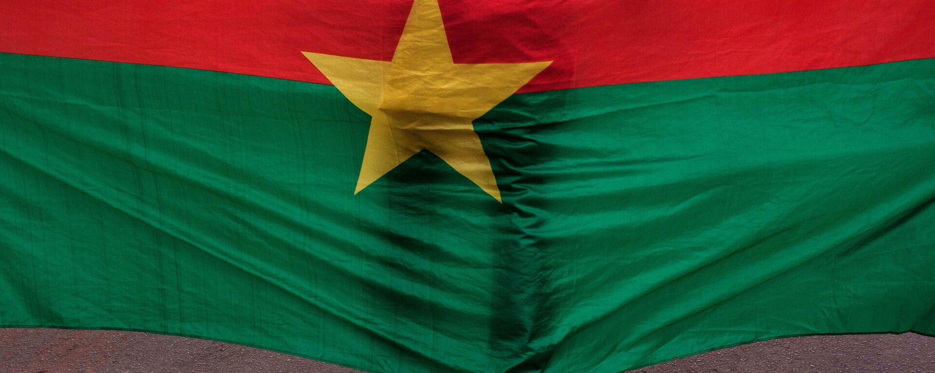 A man stand in front of the Burkina Faso nationals flag during a memorial ceremony for the victims of the recent hotel attack where extremist killed foreigners and Burkina Faso nationals, in Ouagadougou, Burkina Faso, Saturday,  Jan. 23, 2016.  - Sputnik Africa, 1920, 03.03.2024