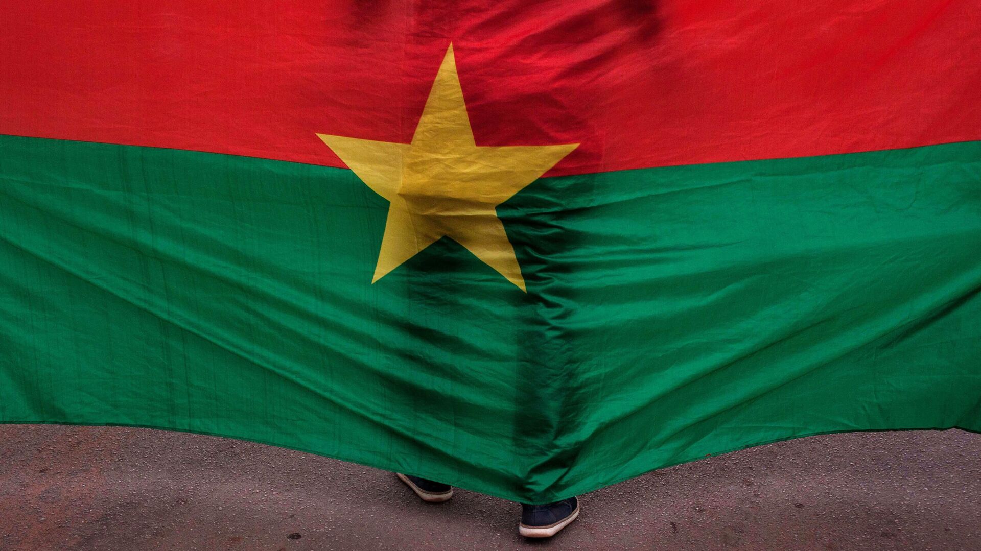 A man stand in front of the Burkina Faso nationals flag during a memorial ceremony for the victims of the recent hotel attack where extremist killed foreigners and Burkina Faso nationals, in Ouagadougou, Burkina Faso, Saturday,  Jan. 23, 2016.  - Sputnik Africa, 1920, 04.05.2024