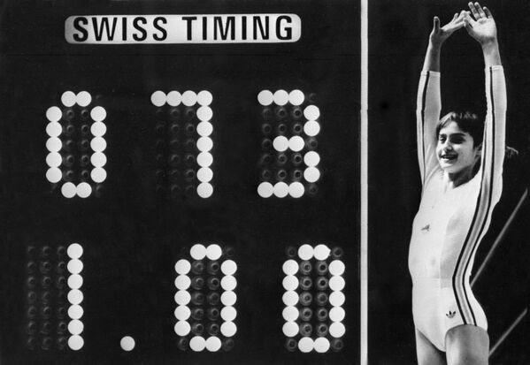 Romanian champion Nadia Comaneci, 14, celebrates as the scoreboard shows a perfect score of 10 after her acrobatic routine on the uneven bars during the Olympic Games in Montreal on July 19, 1976. - Sputnik Africa