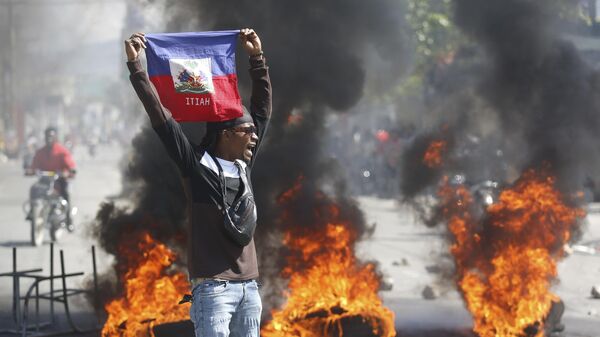 A demonstrator holds up a Haitian flag during protests demanding the resignation of Prime Minister Ariel Henry in Port-au-Prince, Haiti, Friday, March 1, 2024.  - Sputnik Africa