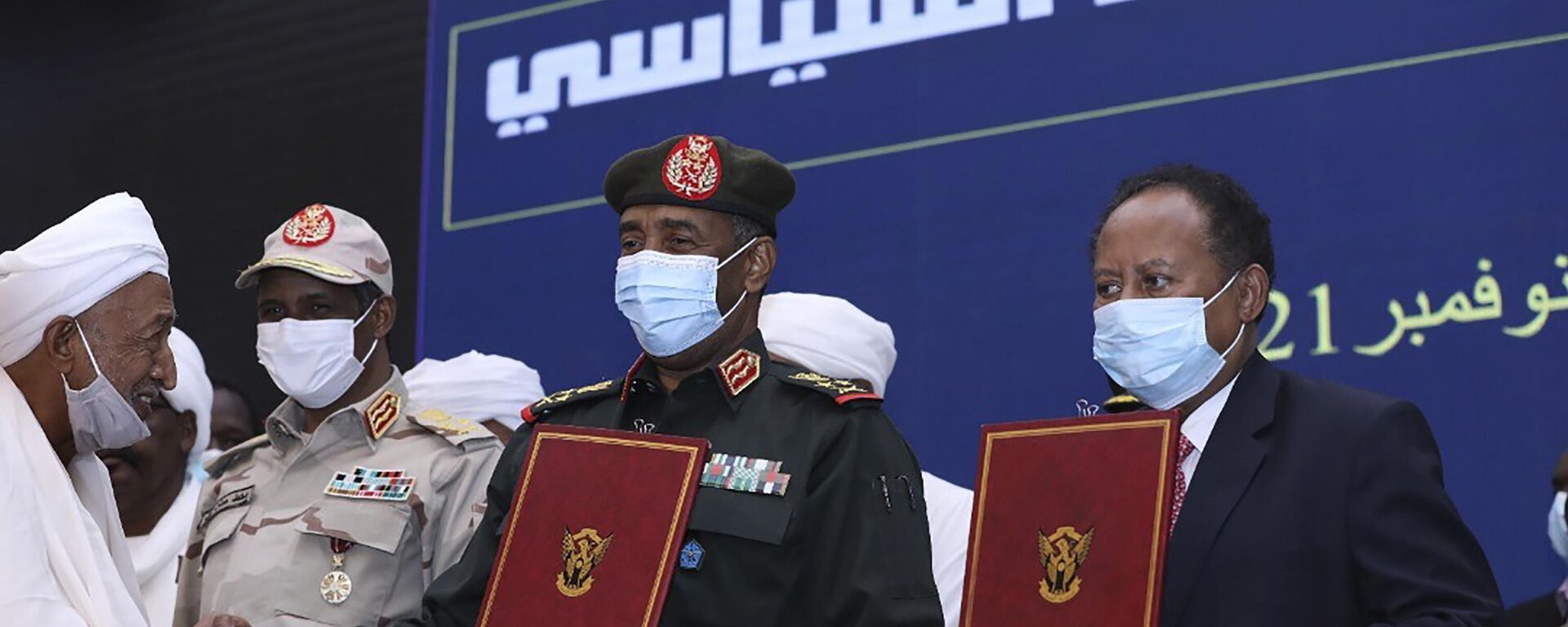 In this photo provided by the Sudan Transitional Sovereign Council, Sudan's top general Abdel Fattah Al-Burhan, center, and then Prime Minister Abdalla Hamdok hold documents attended by Gen. Mohammed Hamdan Dagalo, second left, during a ceremony to reinstate Hamdok, who was deposed in a coup, in Khartoum, Sudan, Nov. 21, 2021. A year after a military takeover upended Sudan’s transition to democracy on Oct. 25, 2021, growing divisions between the two powerful branches of the armed forces are further endangering Sudan’s future. - Sputnik Africa, 1920, 18.02.2025