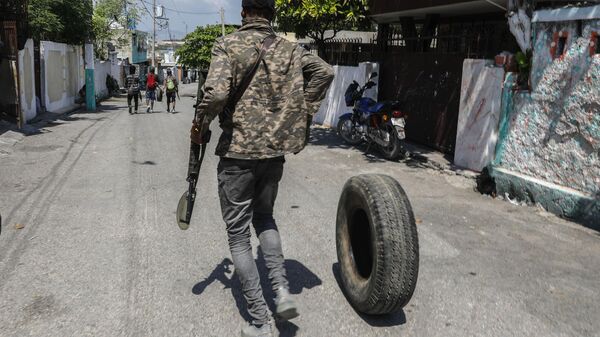 An armed member of the G9 and Family gang rolls a tire to burn at a roadblock in the Delmas 6 neighborhood of Port-au-Prince, Haiti, Monday, March 11, 2024 - Sputnik Africa