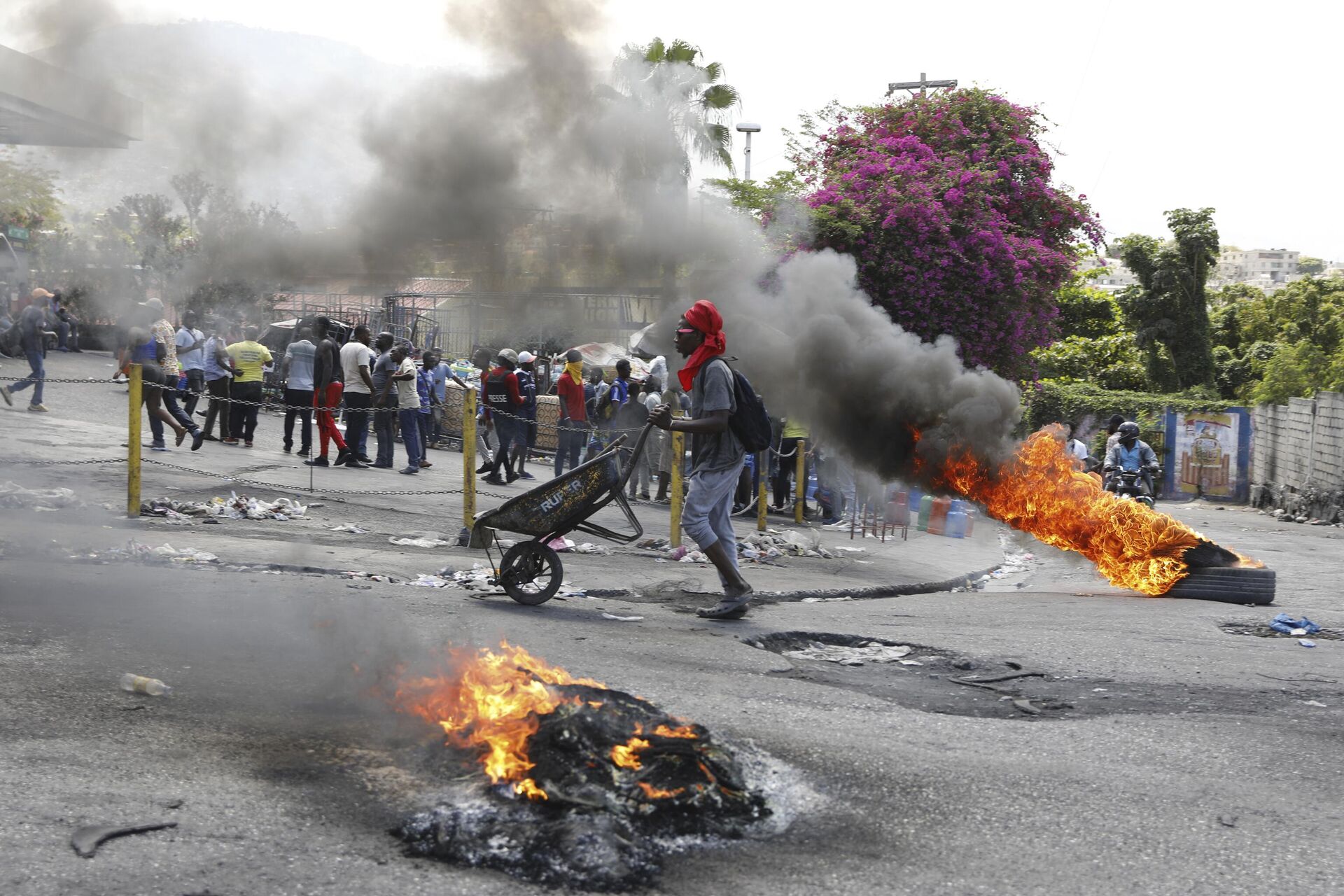A man pushes a wheelbarrow past burning tires during a protest demanding the resignation of Prime Minister Ariel Henry, in Port-au-Prince, Haiti, Thursday, March 7, 2024. - Sputnik Africa, 1920, 12.03.2024