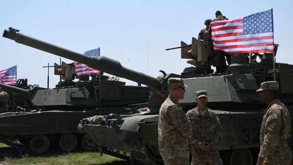 US soldiers stand by Abrams Battle Tanks bearing the US flag ahead of a military drill. File photo. - Sputnik Africa