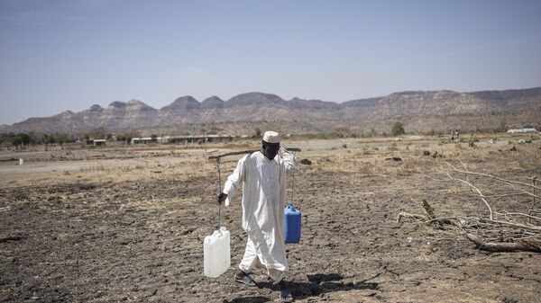 A Sudanese refugee walks back from collecting water in the newly established Awulala refugee camp, near Maganan, 80 km from the Sudanese border in Ethiopia's Amhara region, on February 28, 2024. - Sputnik Africa